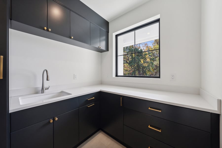 Modern laundry room with black cabinets and white countertops in a custom DesignLab home in Potomac, MD