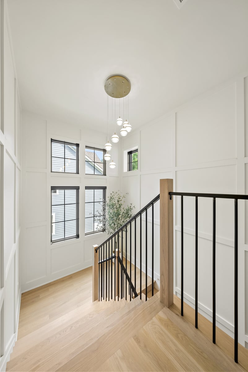 Stairway in remodeled Vienna, VA, home with black railings and large windows