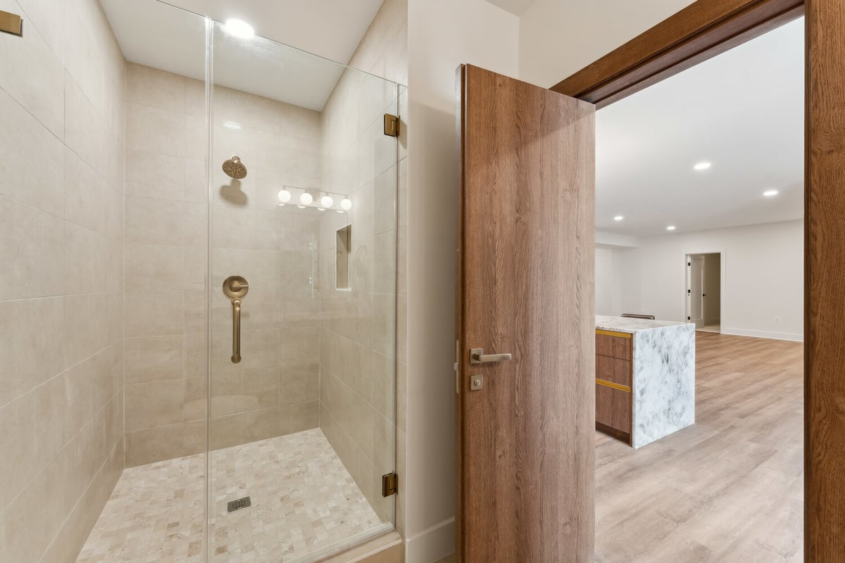 Elegant glass-enclosed shower with neutral tile work in a DesignLab custom home in McLean, VA