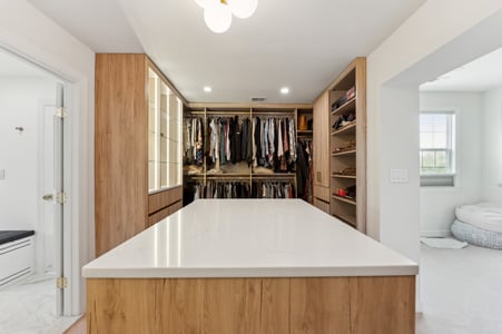 Walk-in primary closet with built in island and shelving in DC Metro home