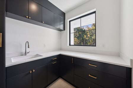Modern laundry room with black cabinets and white countertops in a custom DesignLab home in Potomac, MD