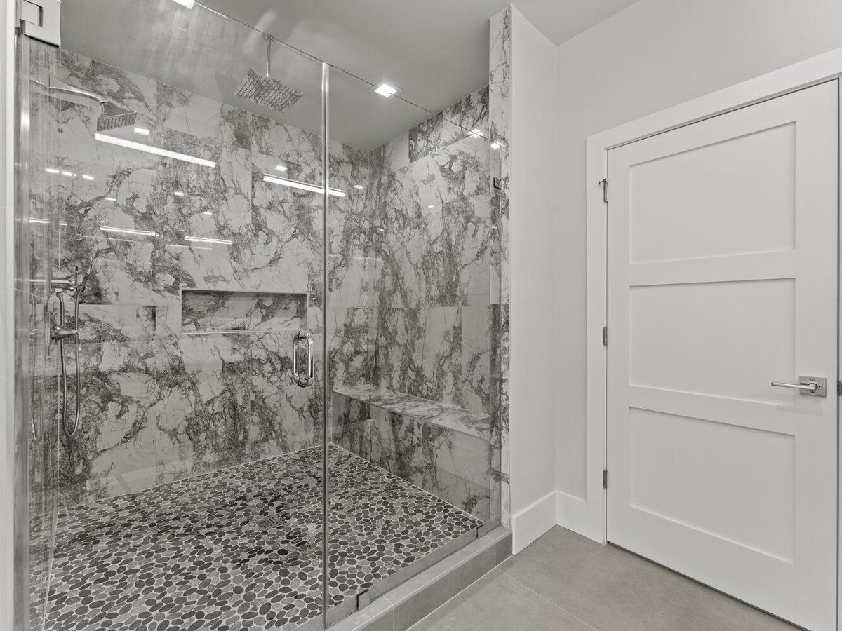 Large marble walk-in shower with glass enclosure in a DesignLab custom home in McLean, VA