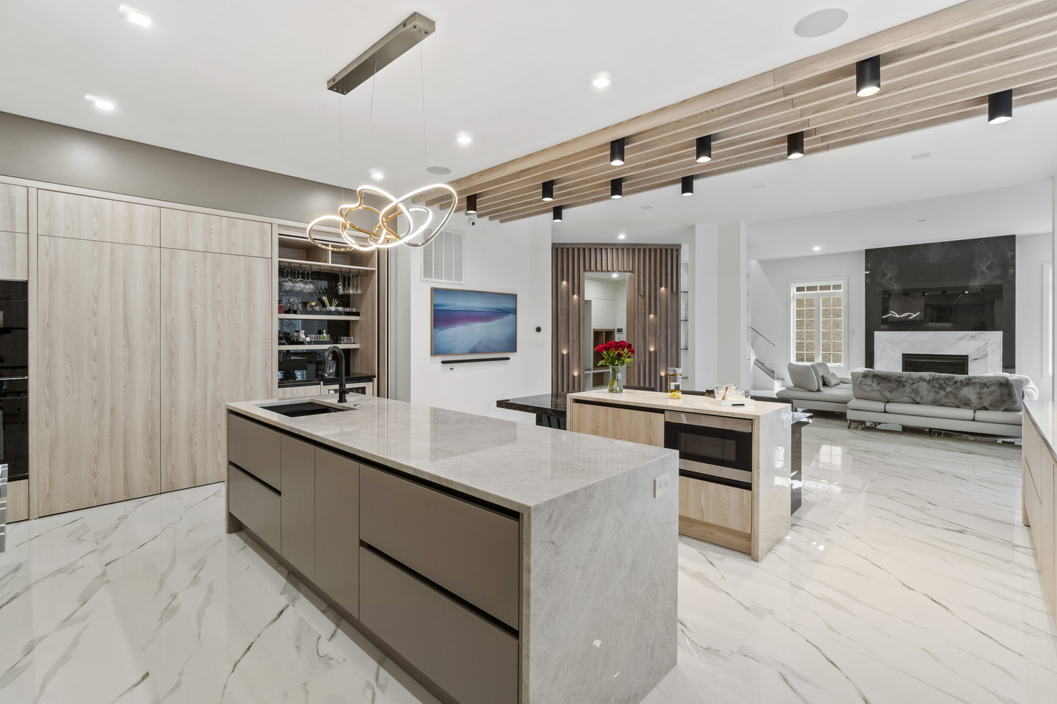 Full view of open-concept kitchen and living room featuring waterfall island and fireplace by DesignLab in Northern VA