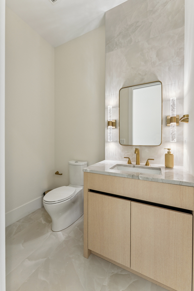 Modern powder room with gold fixtures and marble sink by DesignLab in Washington, DC