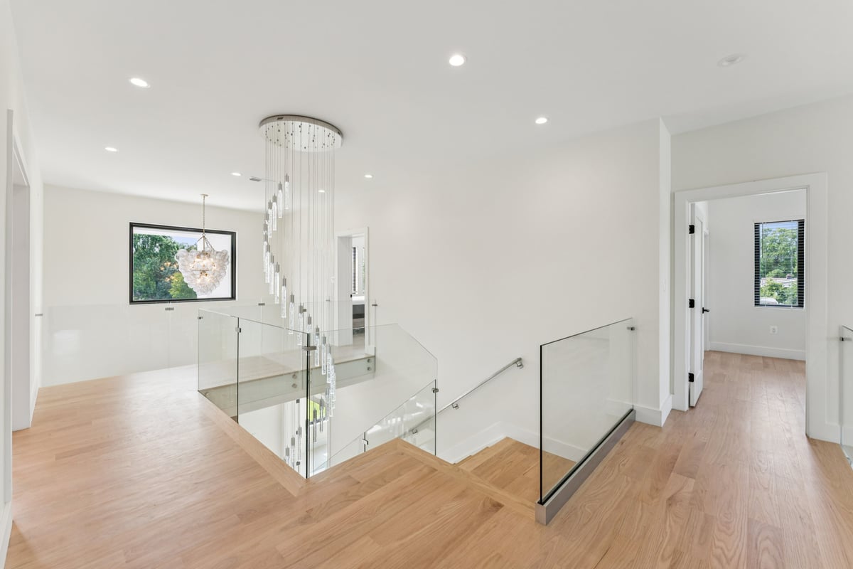 Modern upstairs hallway with glass railing and spiral chandelier by DesignLab in Washington, DC