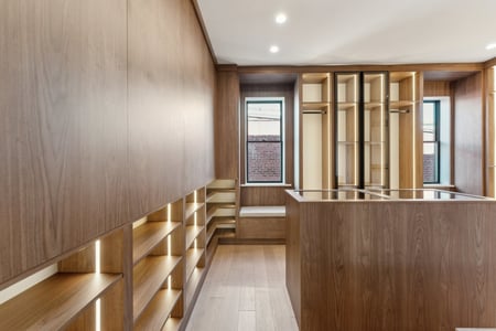 Custom walk-in closet with wood shelving and display island in a DesignLab home in Rhode Island