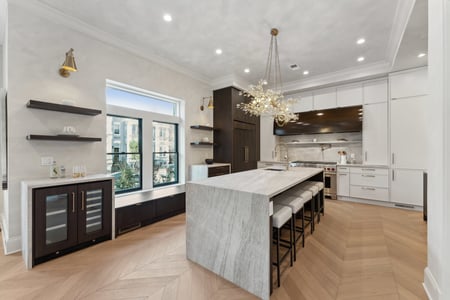 Modern kitchen with waterfall island and statement chandelier in a DesignLab custom home in Rhode Island