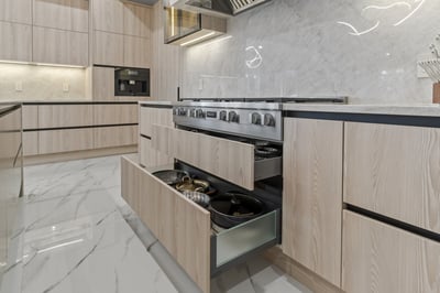 Pull-out drawers below stovetop with cookware storage in a custom kitchen by DesignLab in Metro Washington