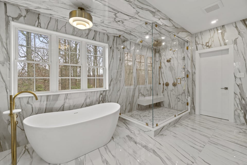 High-end bathroom with marble walls, freestanding tub, and glass shower by DesignLab in Northern Virginia