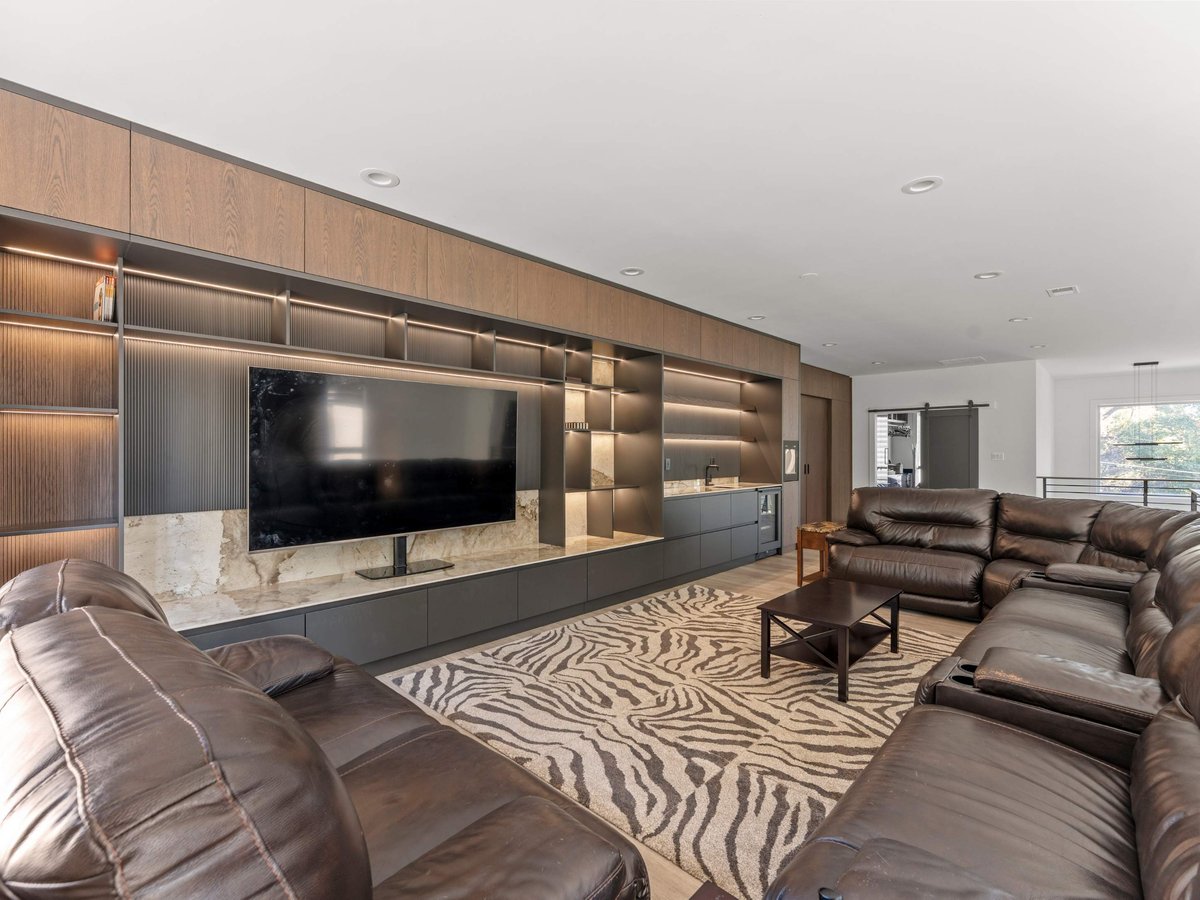 Upstairs entertainment area with layered lighting and custom media wall in Mclean home remodel