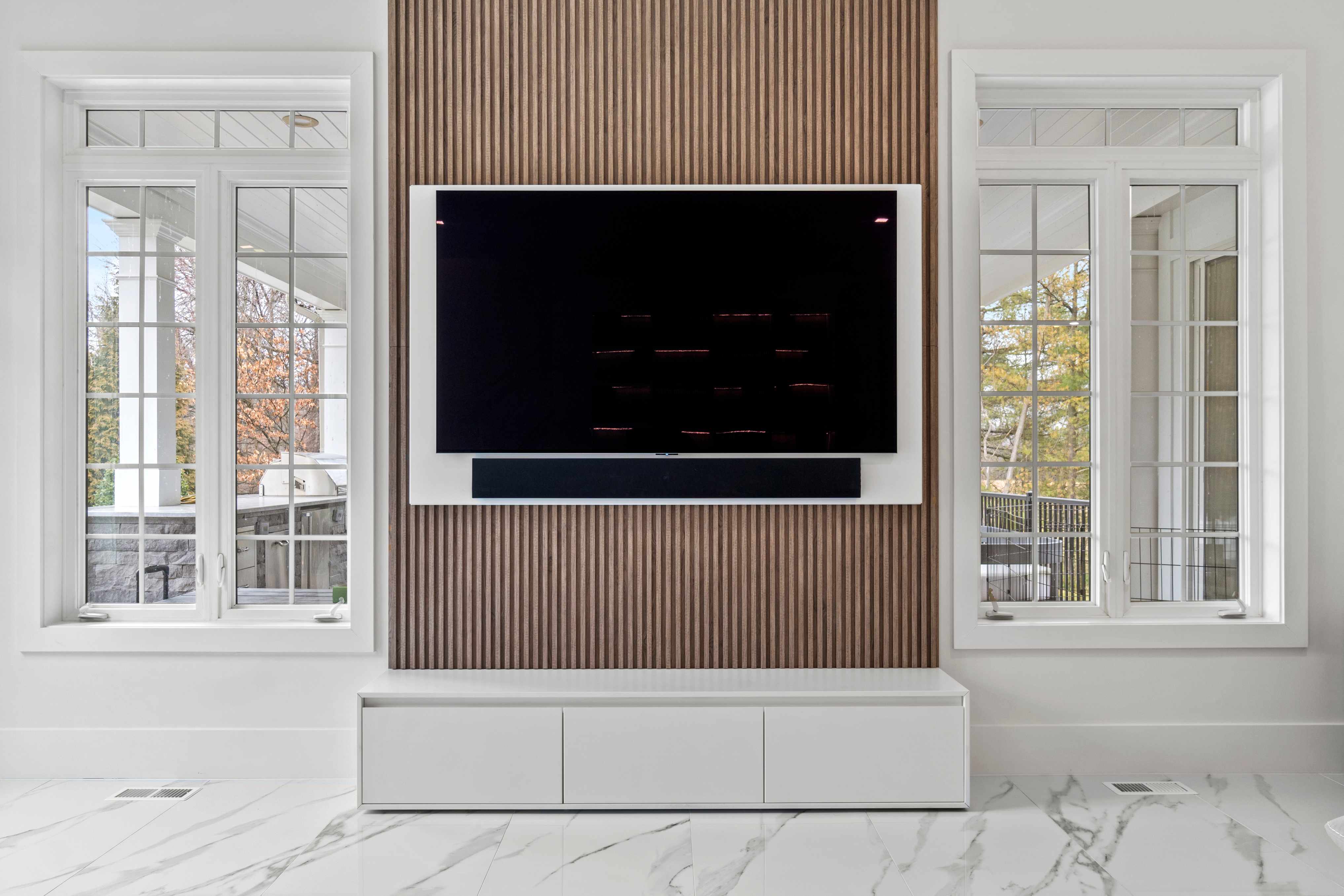 White Cabinetry Console Table with Large Mounted TV Flanked by Ceiling to Floor Windows