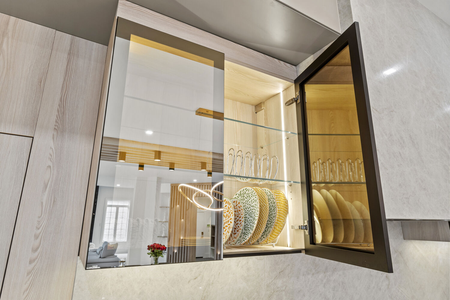 Open glass cabinet with decorative plates and interior lighting in a custom kitchen by DesignLab in Metro Washington