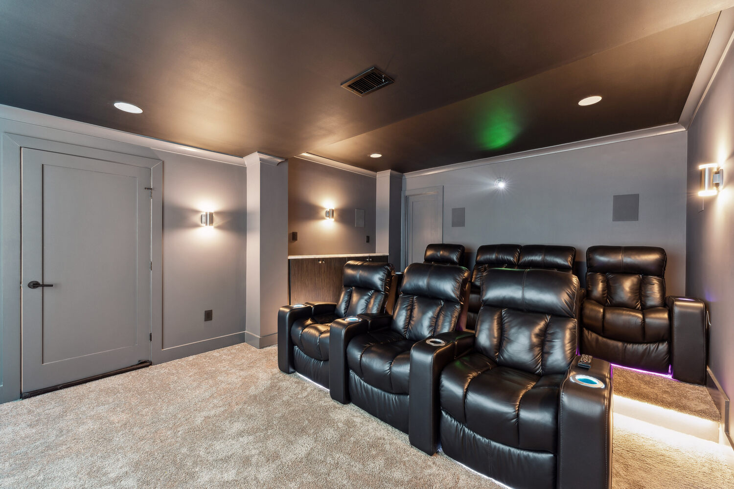 Rear view of basement home theater with recliners and soft carpeting in a Metro Washington custom home by DesignLab