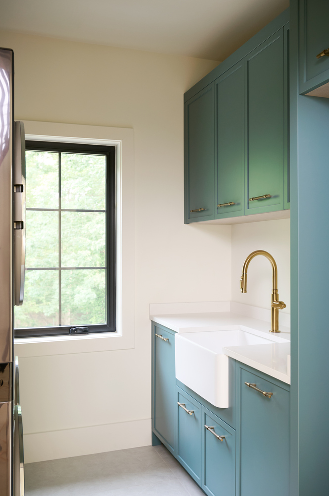 Laundry room with brass faucet and teal cabinetry by DesignLab in a Metro Washington custom home