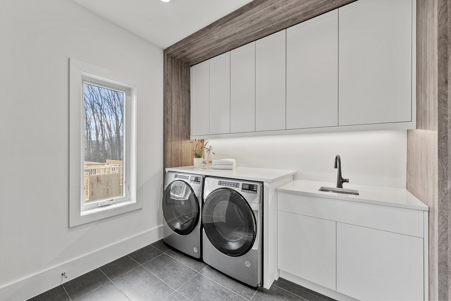 Light-filled laundry area featuring white cabinetry and front-load machines by DesignLab in Metro Washington