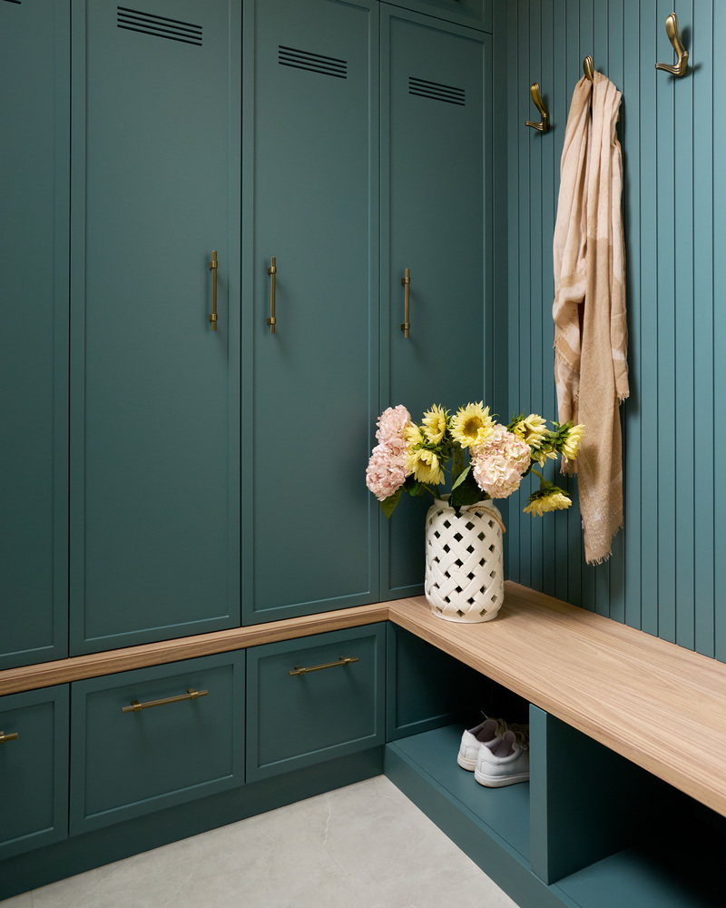 Stylish teal locker-style mudroom with wood bench and floral decor in a DesignLab custom home in Metro Washington