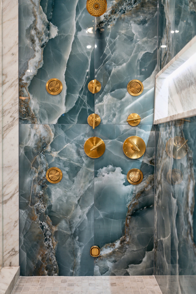 Close-up of gold fixtures on dramatic blue onyx shower wall by DesignLab in Metro Washington
