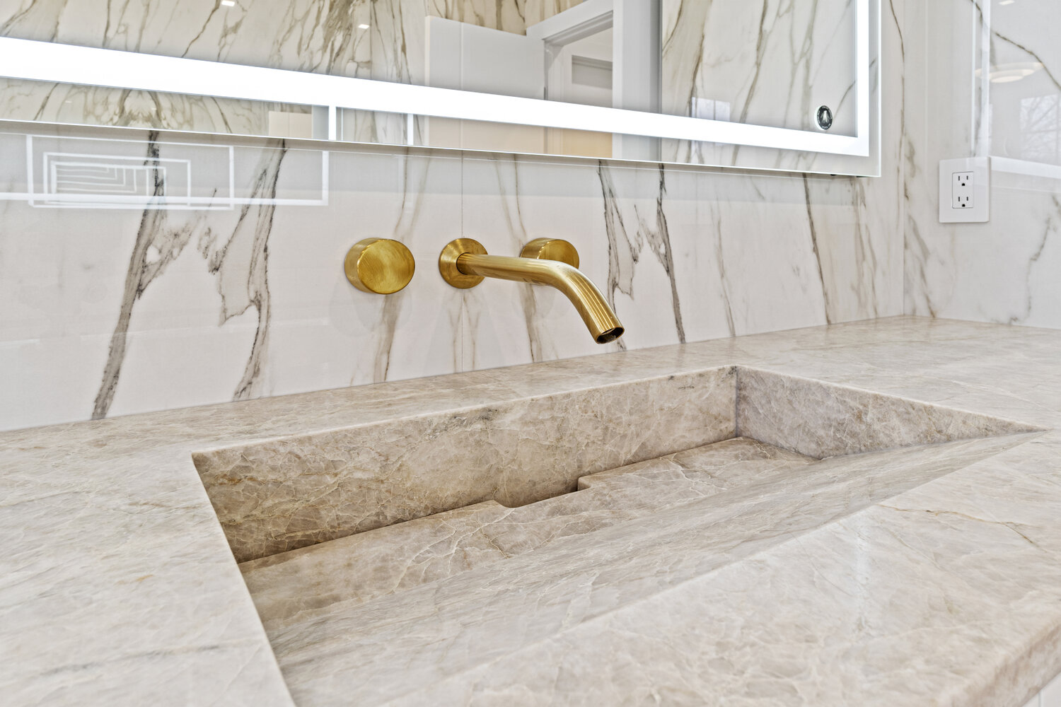 Luxurious stone bathroom sink with integrated design and gold fixtures by DesignLab in Metro Washington custom home