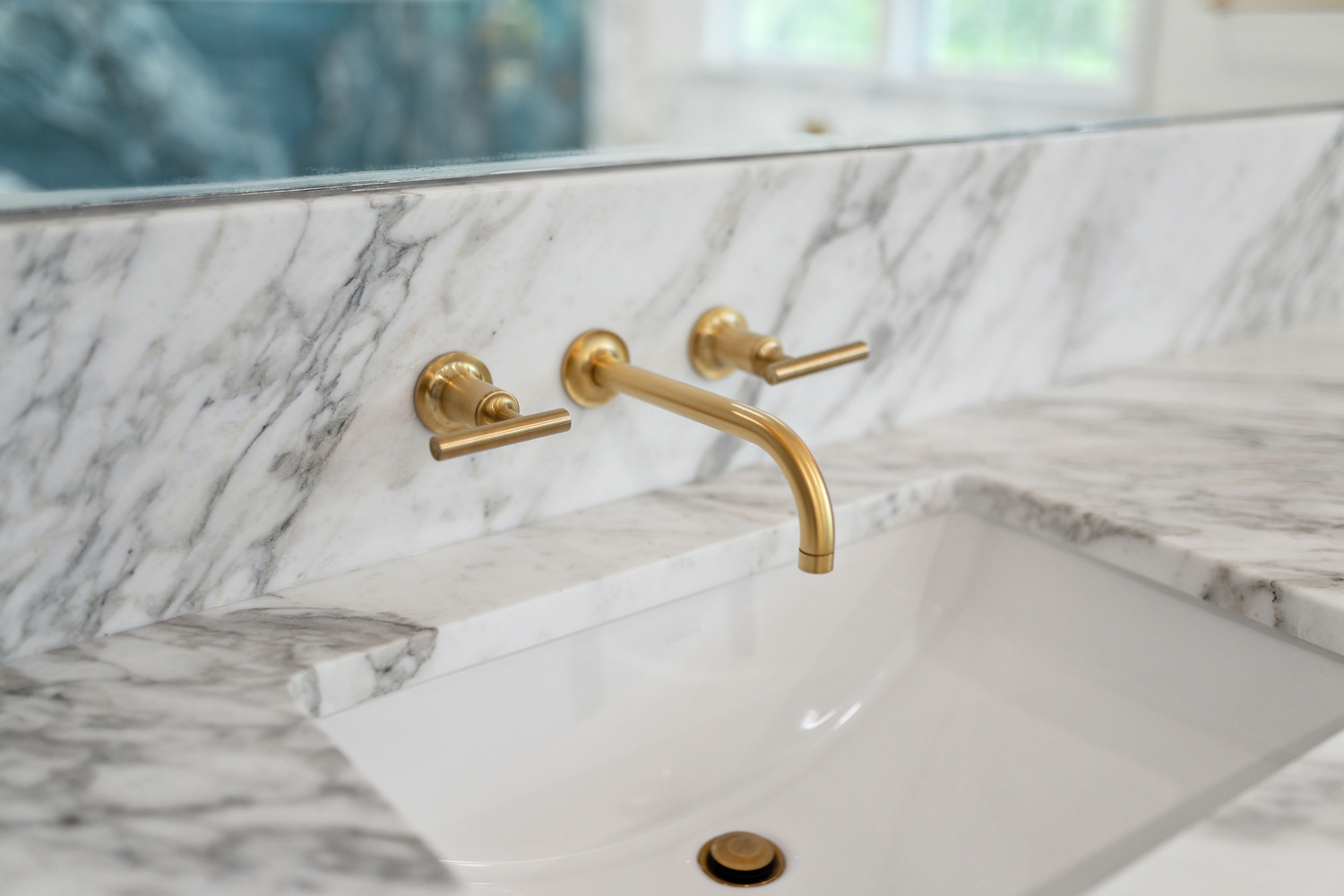 Marble vanity detail with gold wall-mounted faucet by DesignLab in a custom Metro Washington home