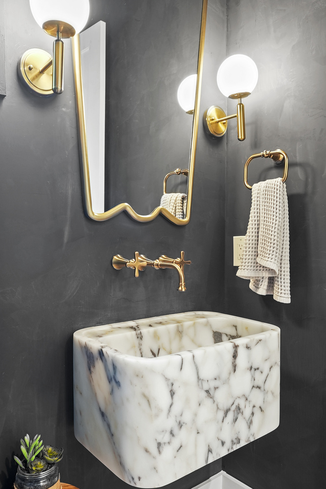 Small powder room with marble sink, curved mirror, and brass accents by DesignLab in Metro Washington