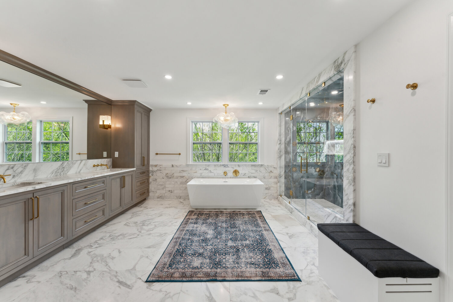 Spacious marble primary bathroom with glass shower, custom cabinetry, and soaking tub by DesignLab in Metro Washington