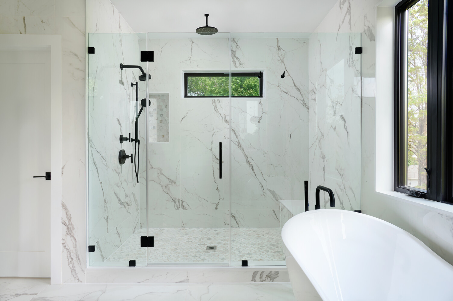 Walk-in shower with minimalist black accents in a Metro Washington custom home by DesignLab
