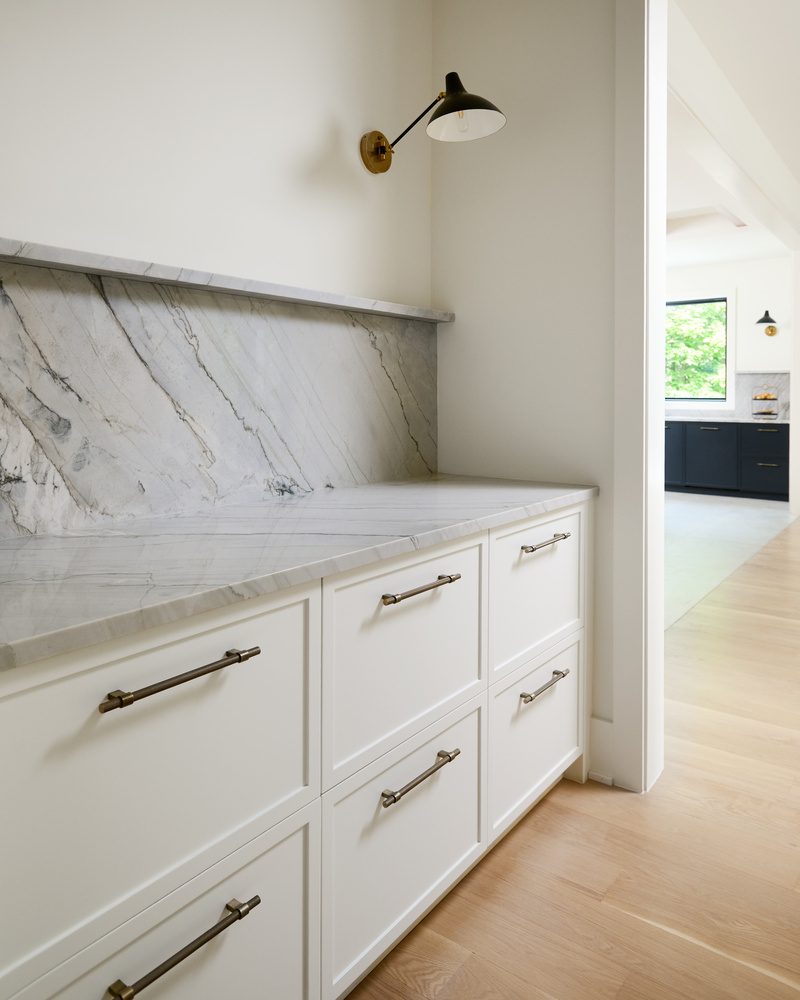 White cabinetry with natural stone backsplash in a Metro Washington custom home by DesignLab
